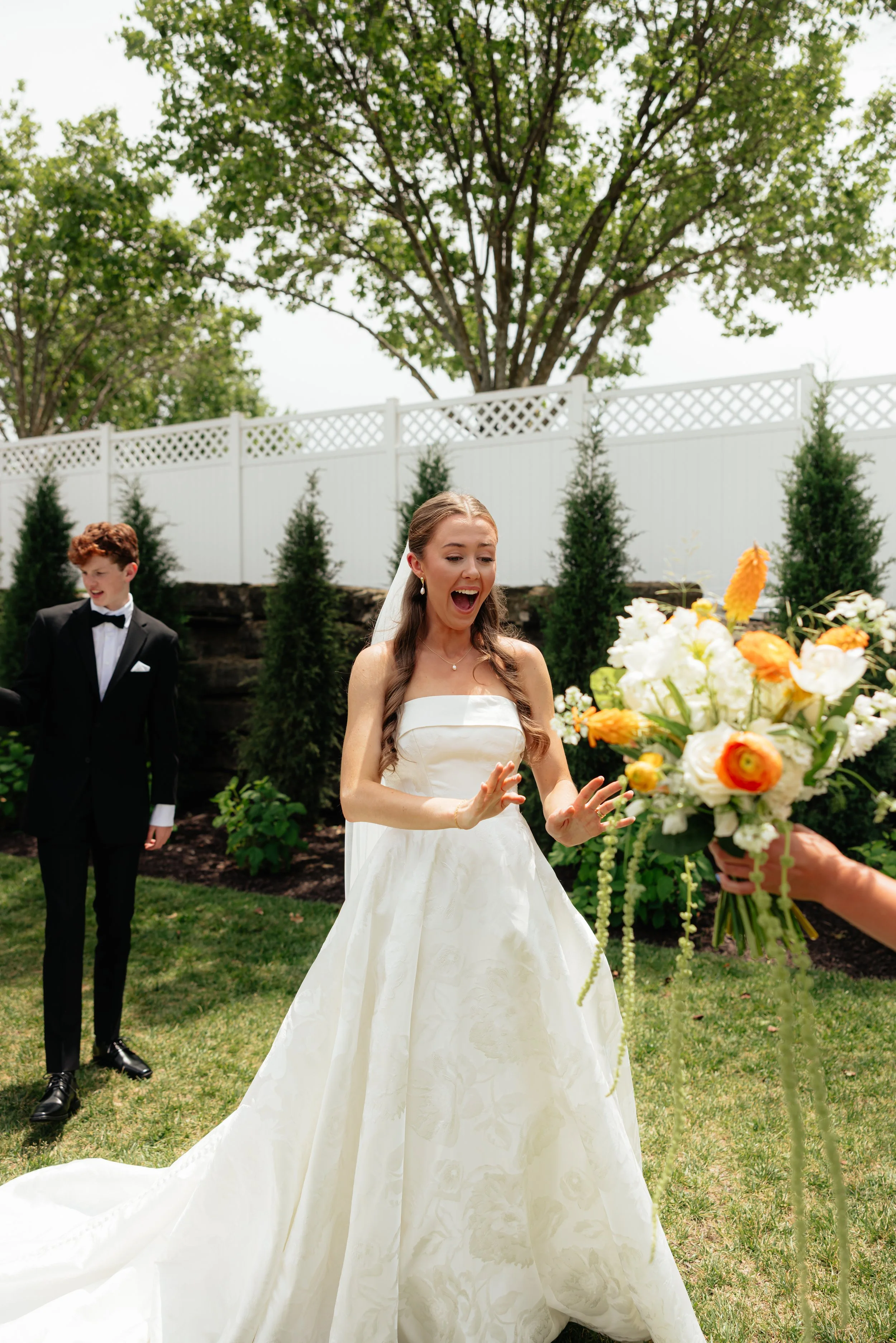 Extremely excited bride seeing her elegant bridal bouquet featuring seasonal blooms and thoughtfully layered floral textures.