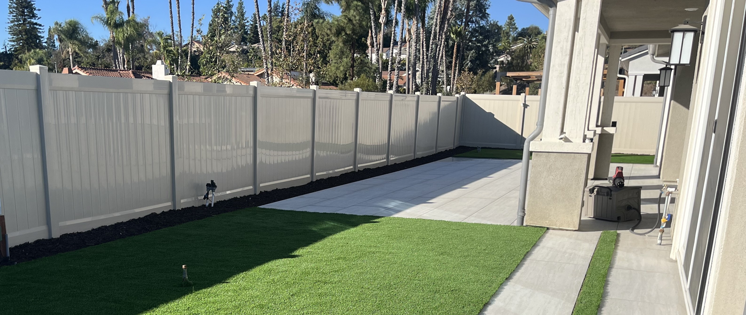 Vinyl privacy fence with porcelain pavers for a custom outdoor living project in Poway, CA.