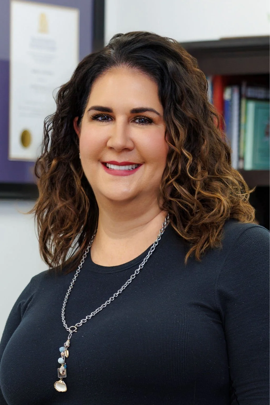 Image of Dr. Virginia South. She is wearing a black shirt with a necklace. She has brown wavy hair and is smiling.