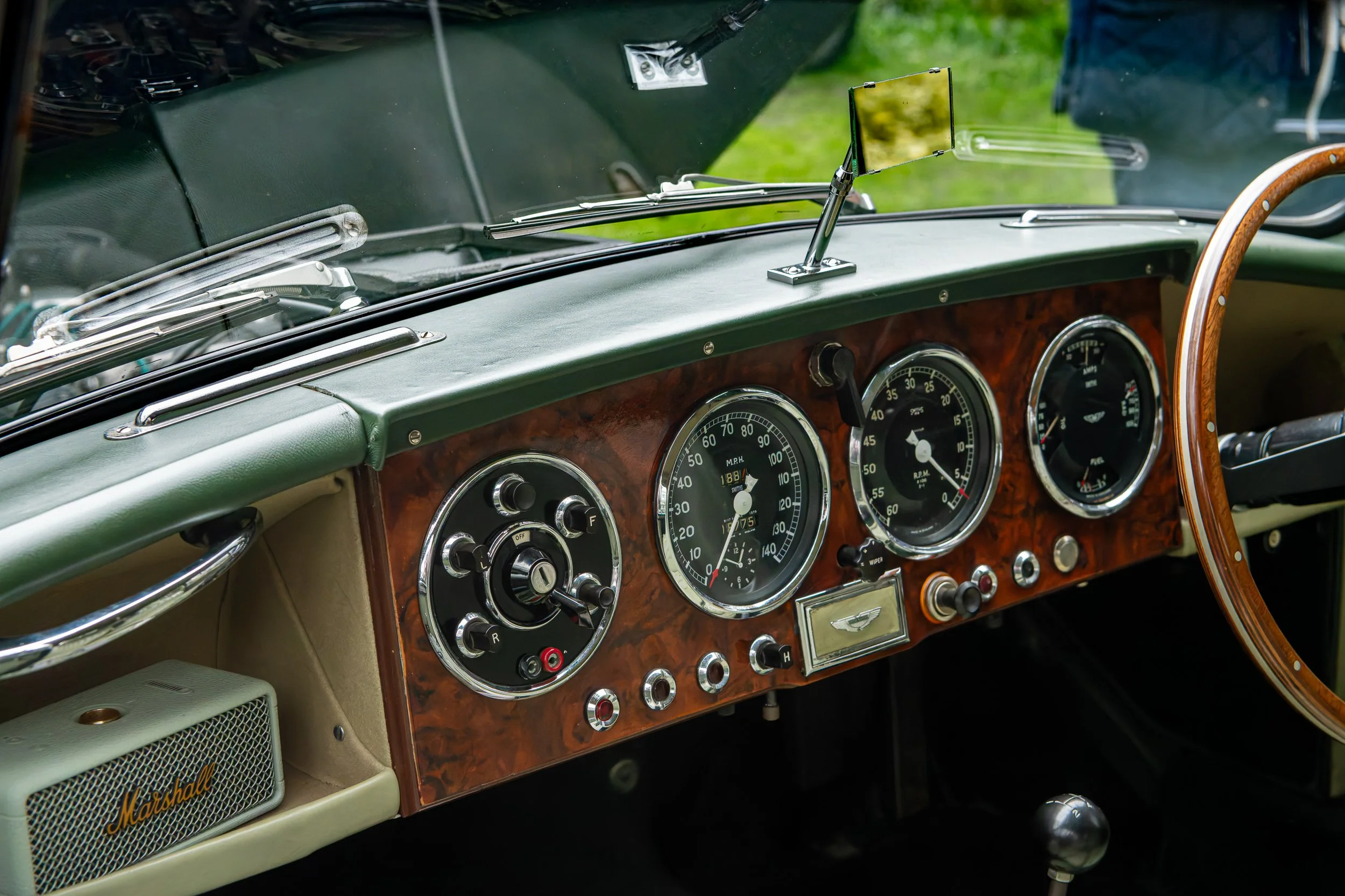 Close-up of the dashboard of a vintage car with wood paneling, classic gauges, and a wooden steering wheel.