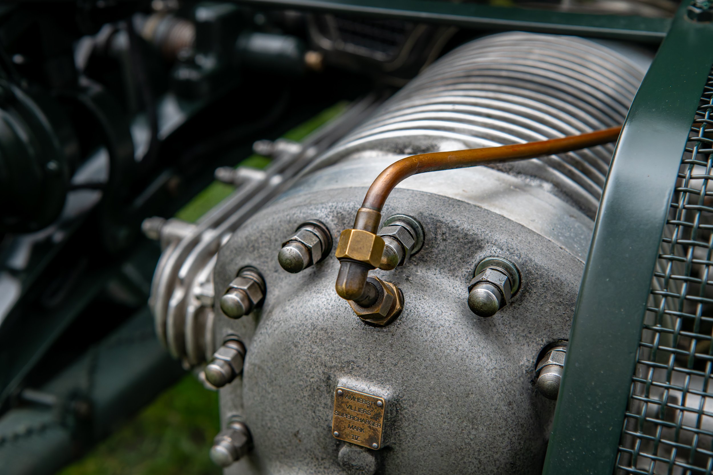 Close-up of a vintage engine with metallic components and a small brass plaque that reads 'Amherst Villiers Supercharger Mark IV.'
