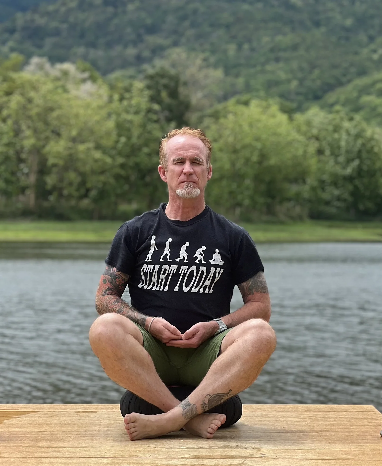 Chris sitting quietly in reflection outdoors by the water in Chiang Mai