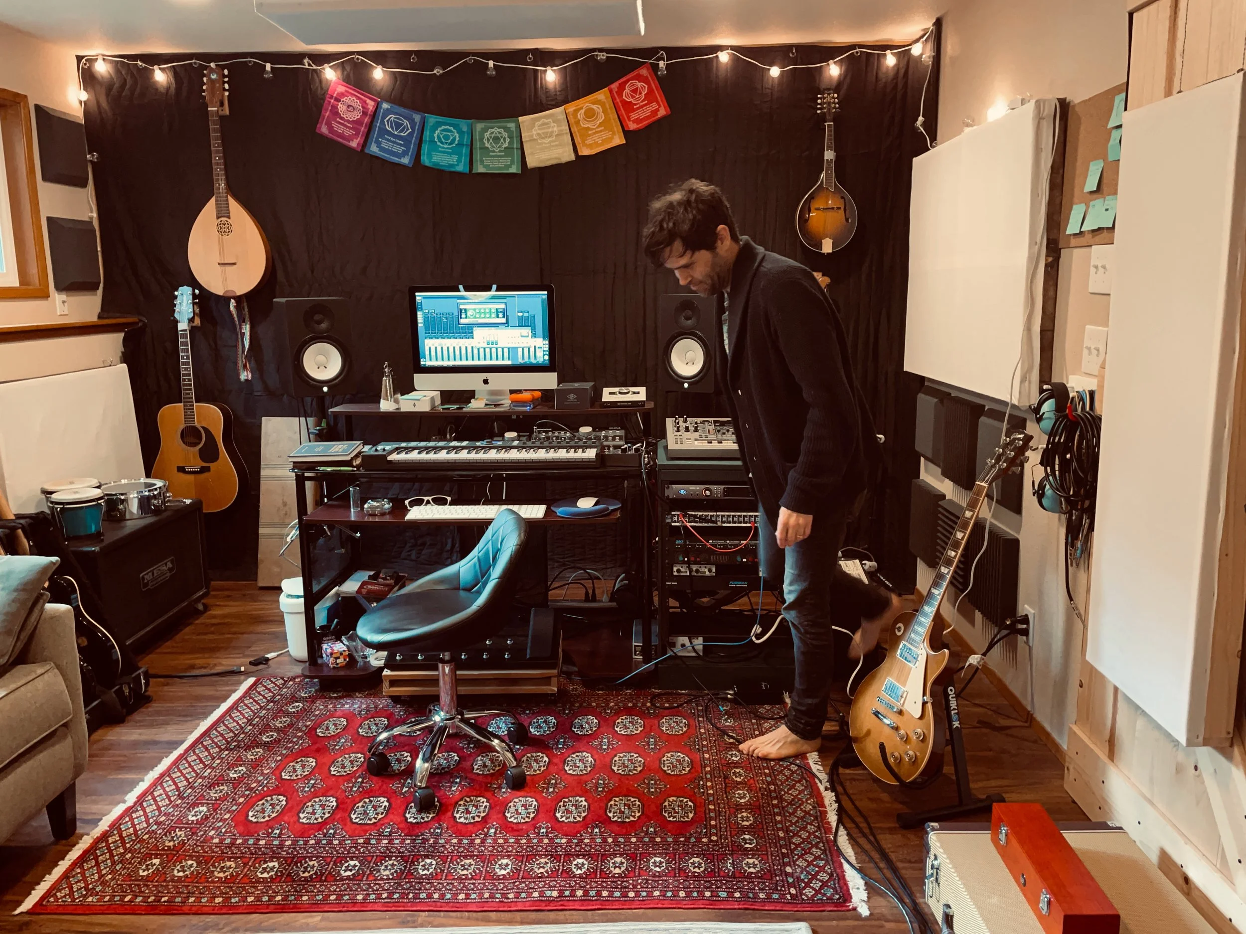 Home music studio with instruments, computer, and recording equipment on a decorative rug.