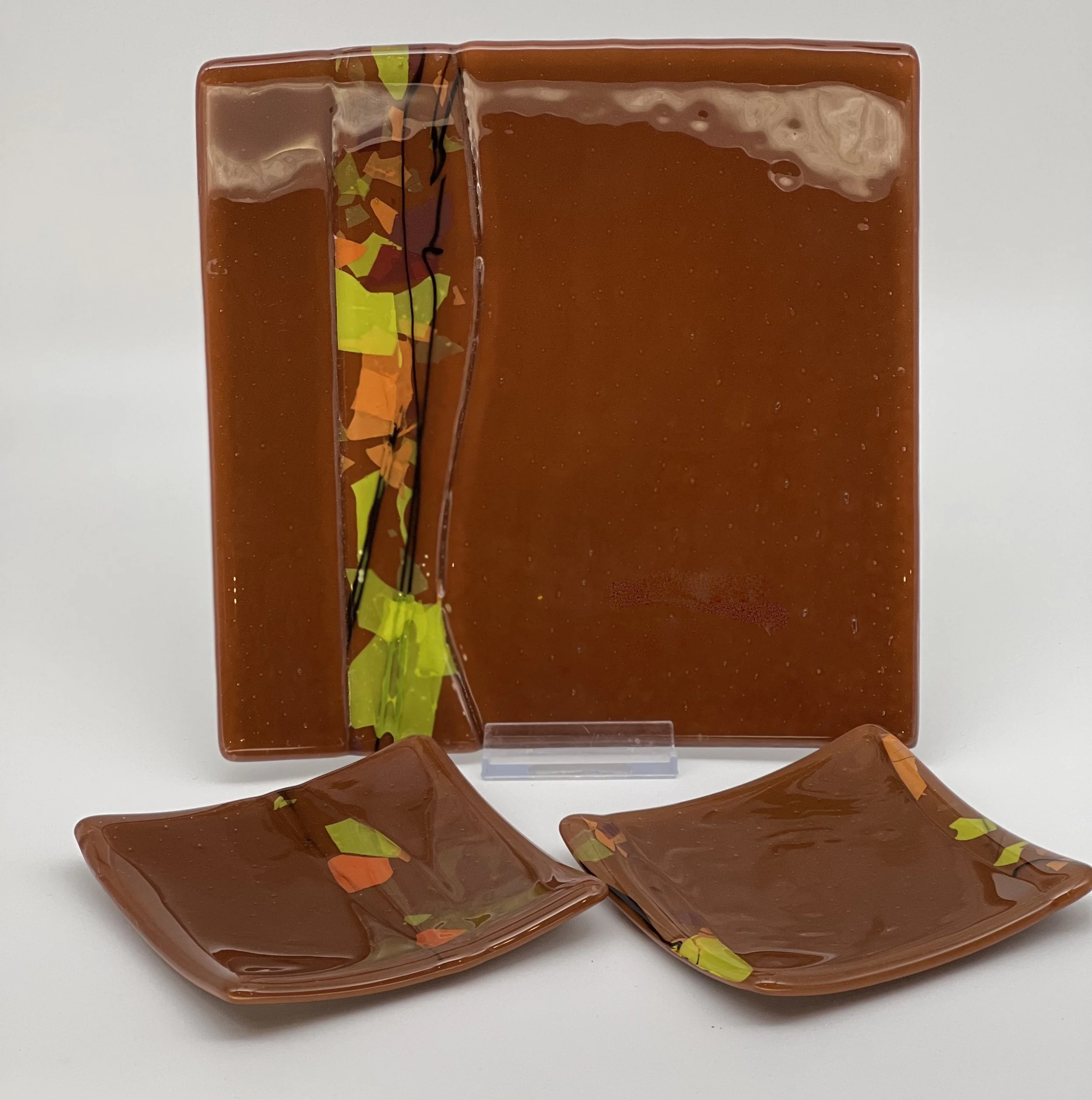 Burnt Orange base with clear overlay and autumn confetti insets.  Large plate is 8.5" square, small plates 4.5"square $75/set