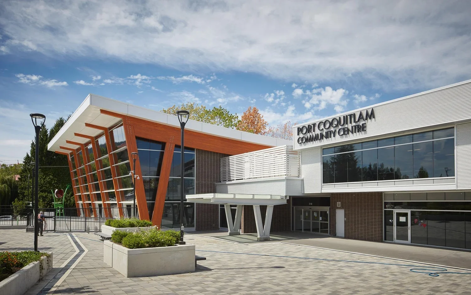 Exterior view of Fort Coquitlam Community Centre with modern architectural design, large glass windows, and a sign showing its name.