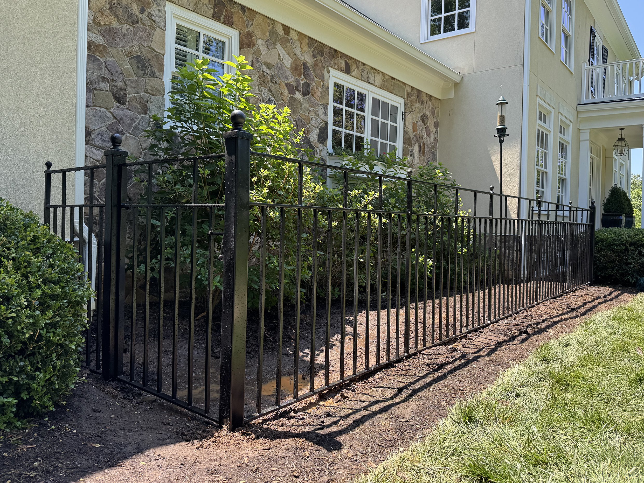 Black wrought iron fencing surrounding a home's flower bed