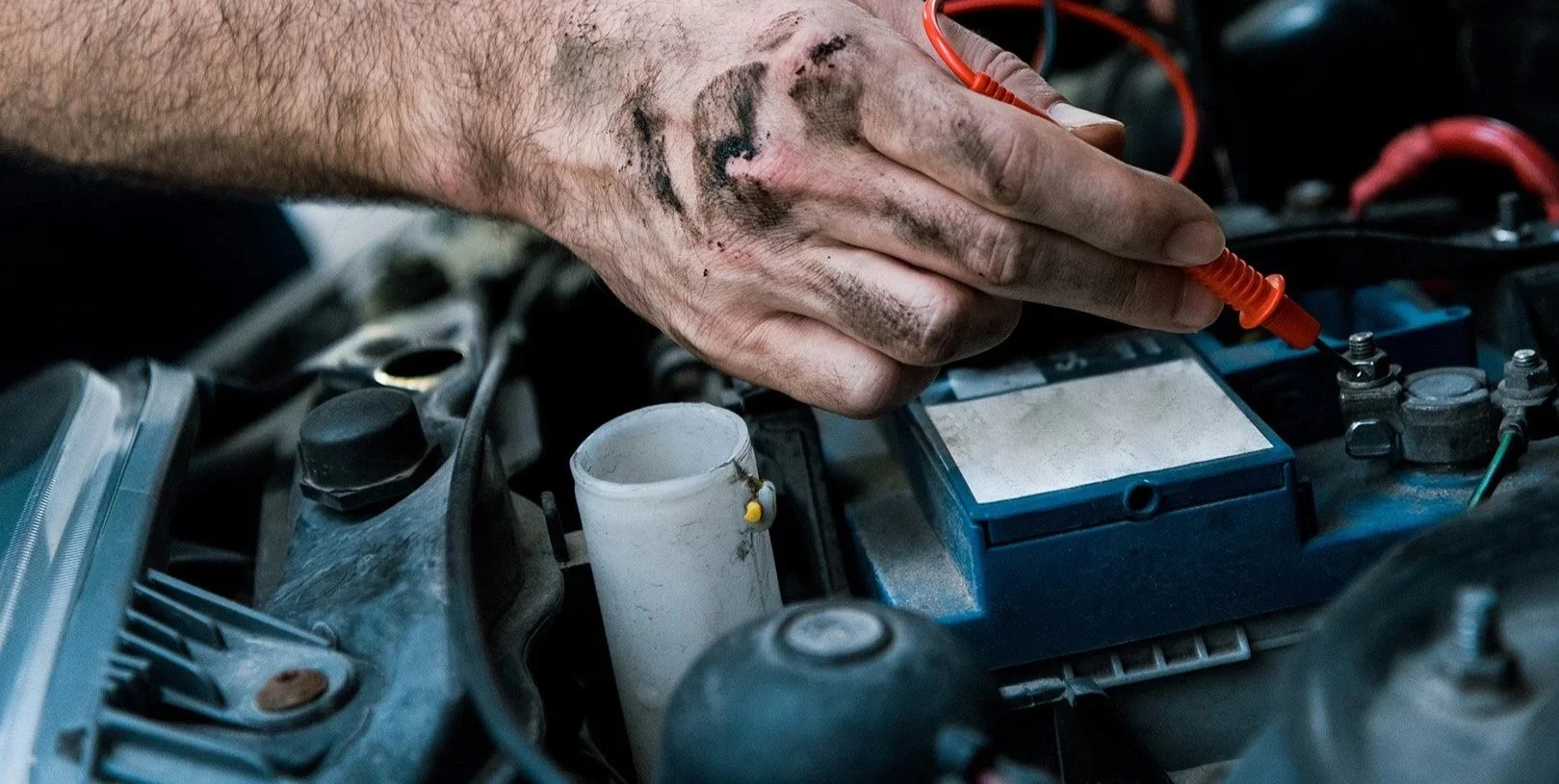 Image of a man's hand repairing an automobile motor