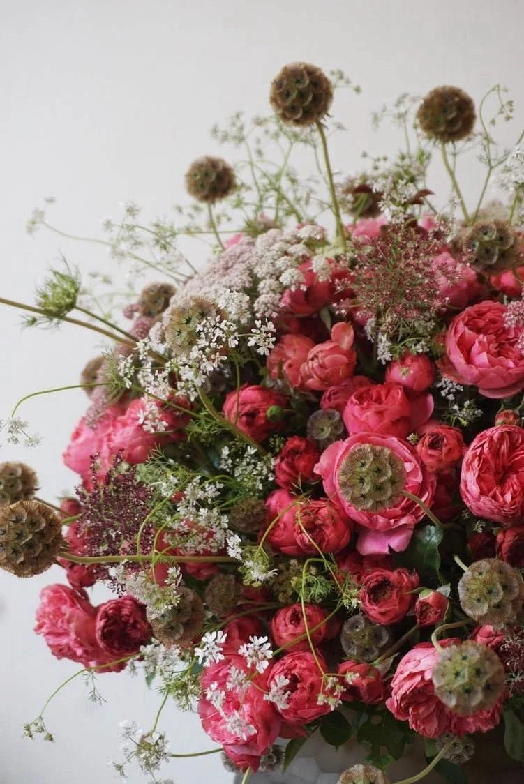 Un bouquet de fleurs avec des roses roses, des petites fleurs blanches et des graines de fleurs sèches.
