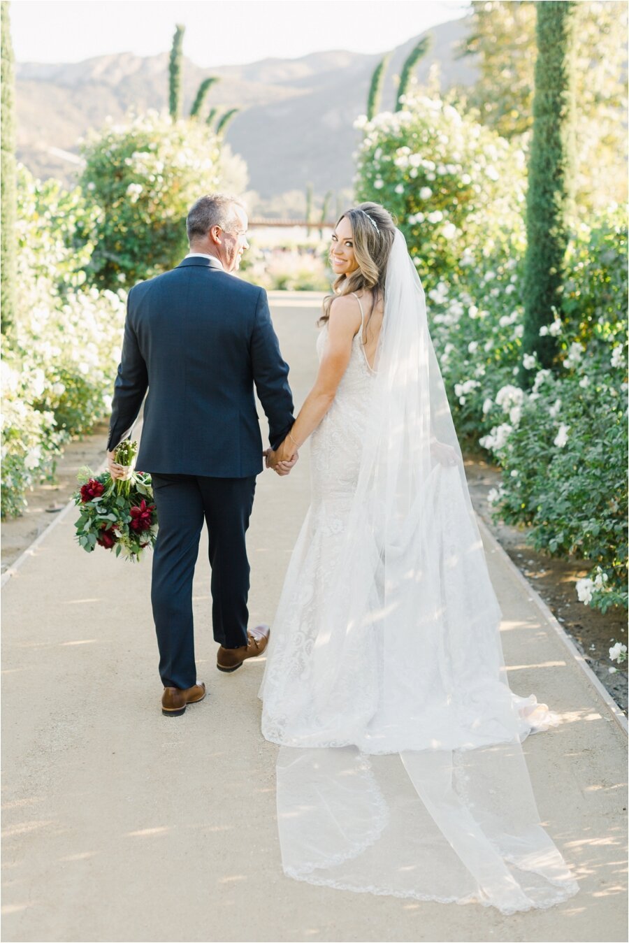 Bride and groom walk through vineyard together