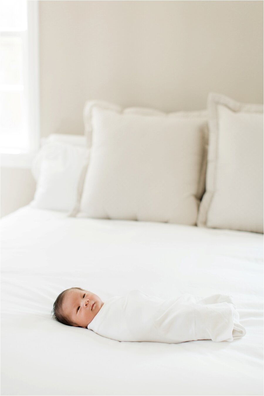 swaddled newborn baby on white bed