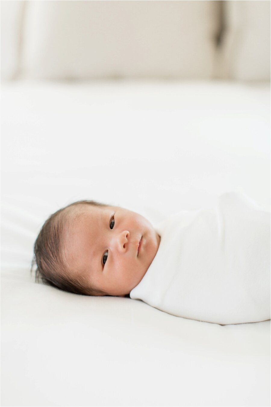 newborn baby wrapped in white swaddle cloth