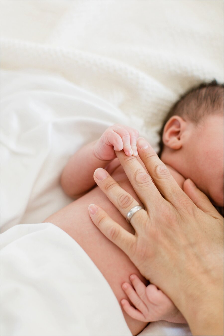 newborn baby grasps father's fingers