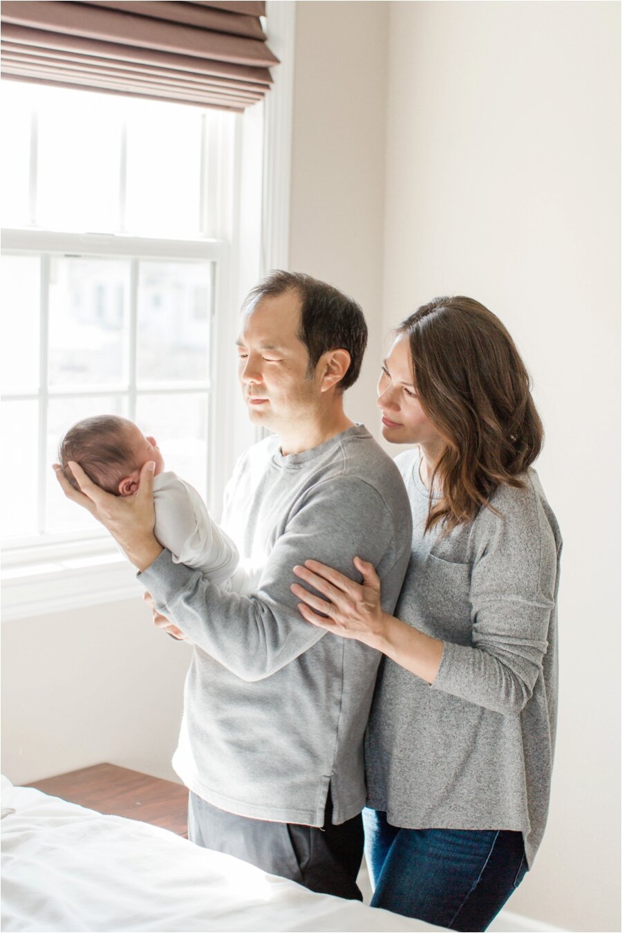 Mom and dad pose with Newborn son in window light