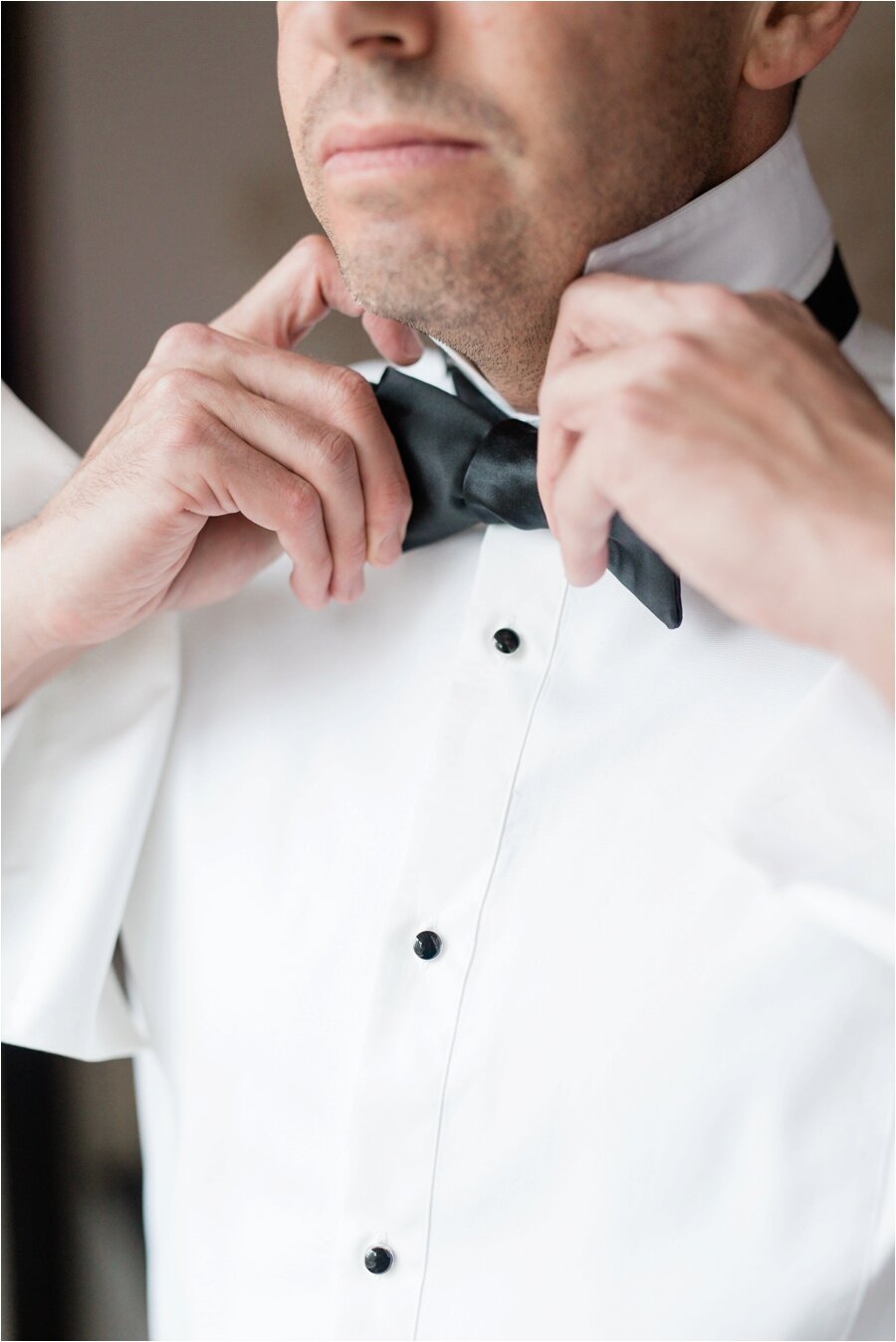groom tying his bow tie in hotel room at The Peninsula Chicago