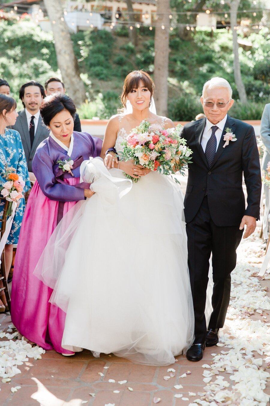 bride walks down the aisle with mom and dad 