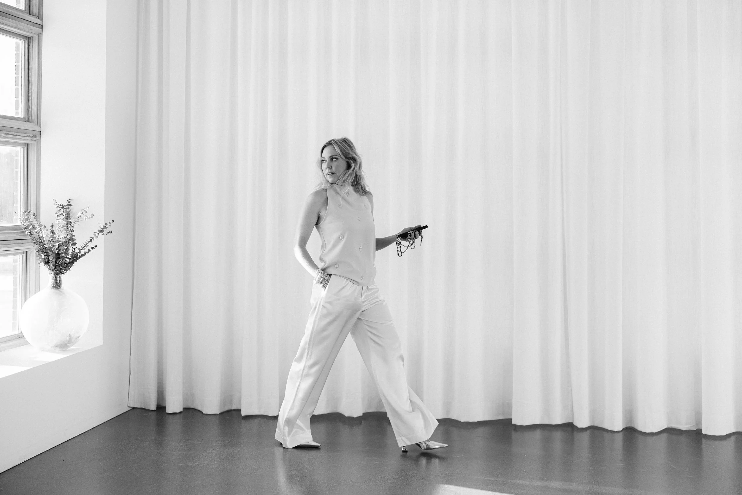 Kathryn Snow, personal stylist, fashion expert, and wardrobe consultant in Grand Rapids, Michigan, holding a smartphone in her right hand and looking to her left.