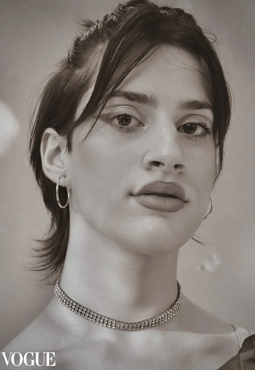 Ragazza con orecchini a cerchio e collana di cristalli, capelli corti e sguardo diretto, in bianco e nero, copertina di Vogue.