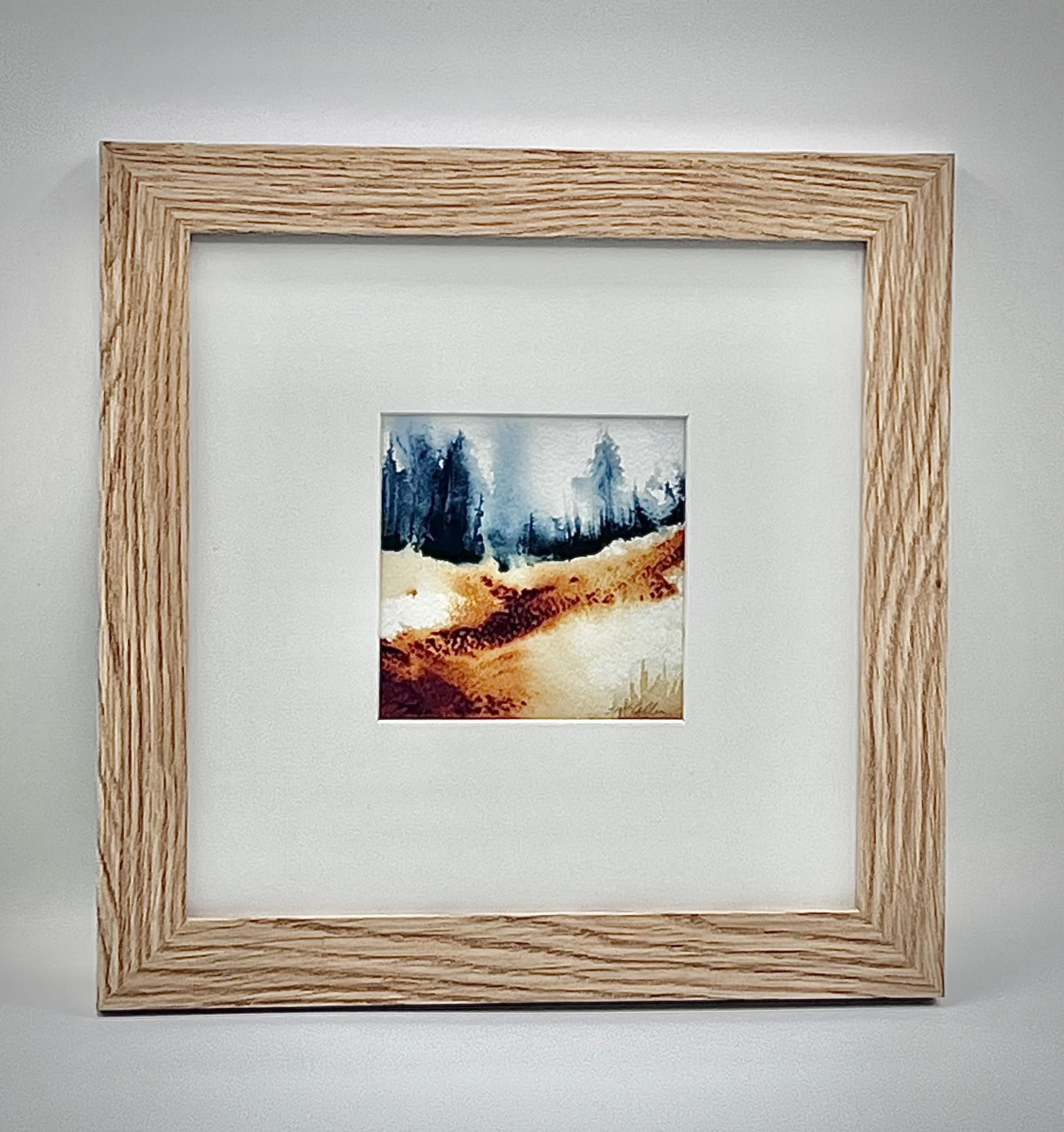 framed image of tan and Sienna hills against blue green treeline in the distance