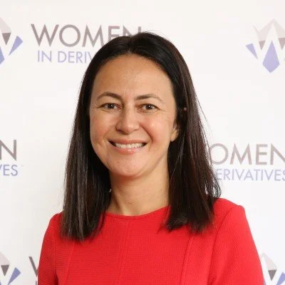 Woman in a red blouse smiling at Women in Derivatives event backdrop.