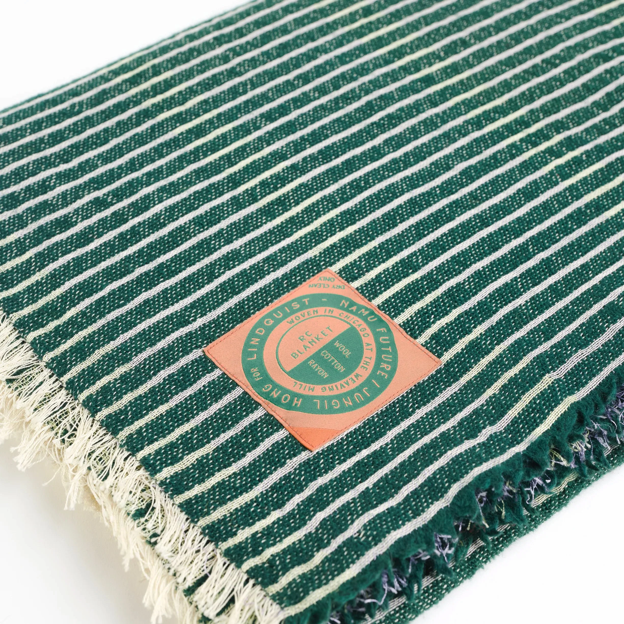 A folded green and white striped blanket with a coral-colored sewed on to it