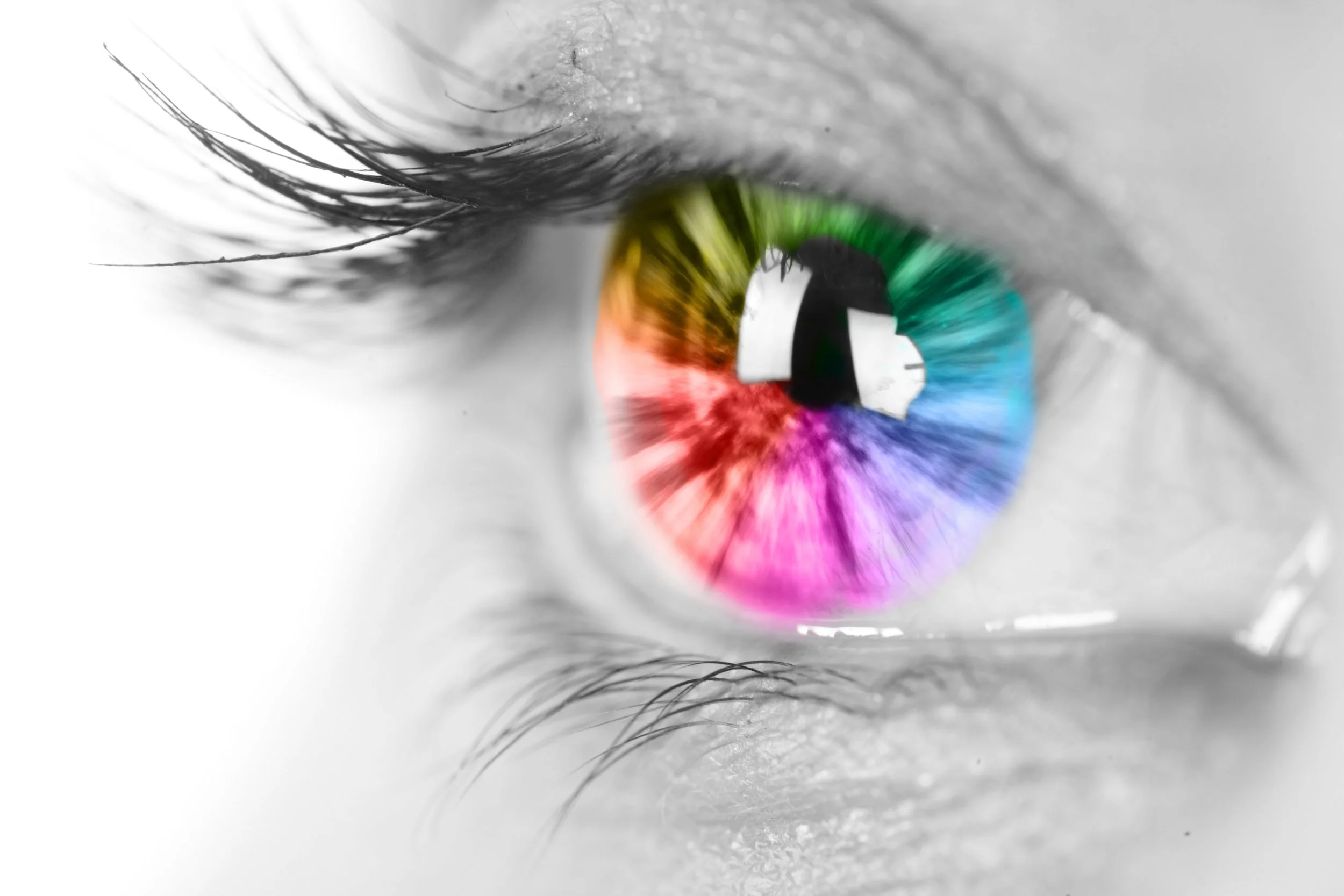 Close-up of a human eye with a colorful rainbow iris reflection, black and white skin and eyelashes.
