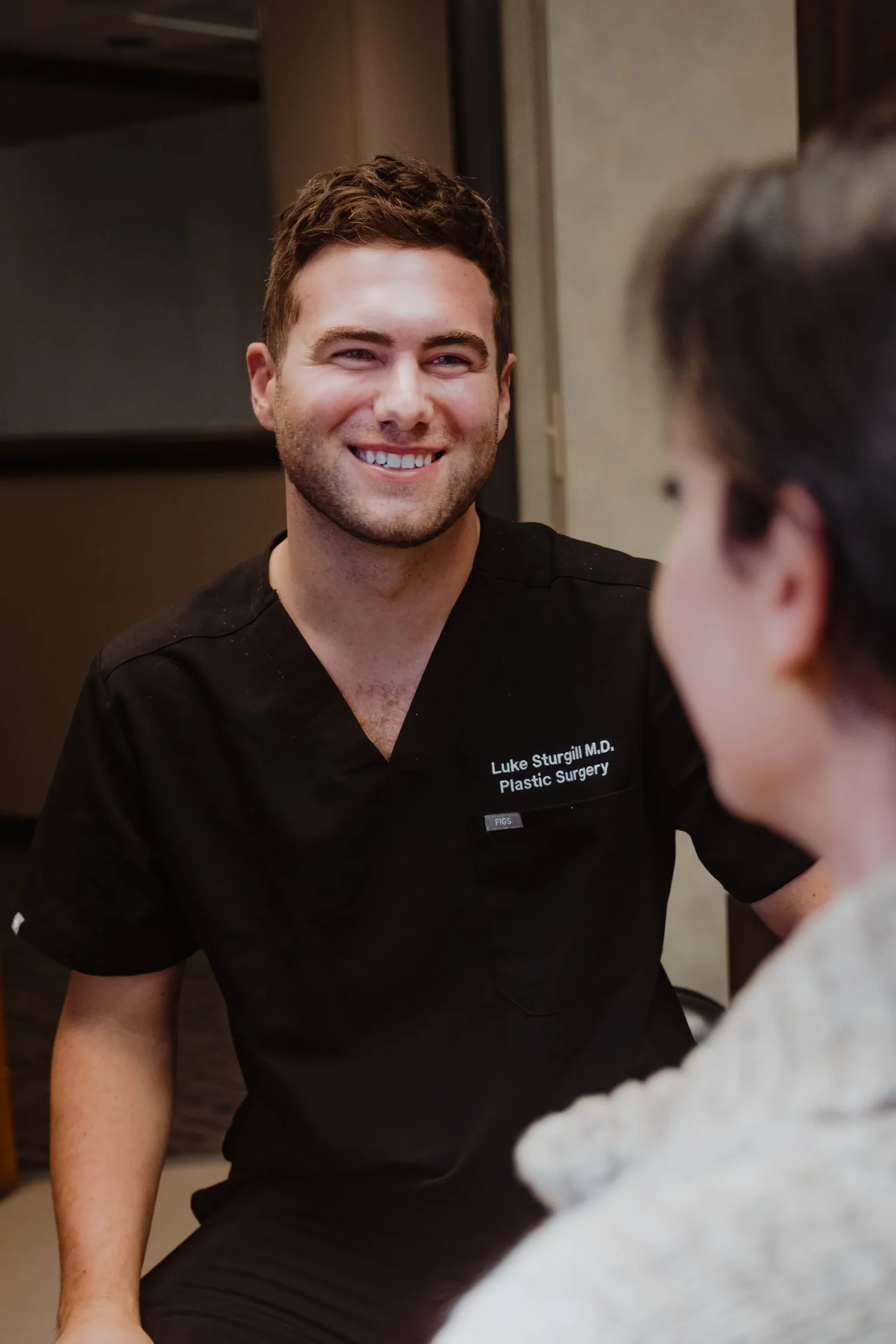Dr. R. Luke Sturgill examining a patient’s face during a skin resurfacing consultation in Carmel, Indiana