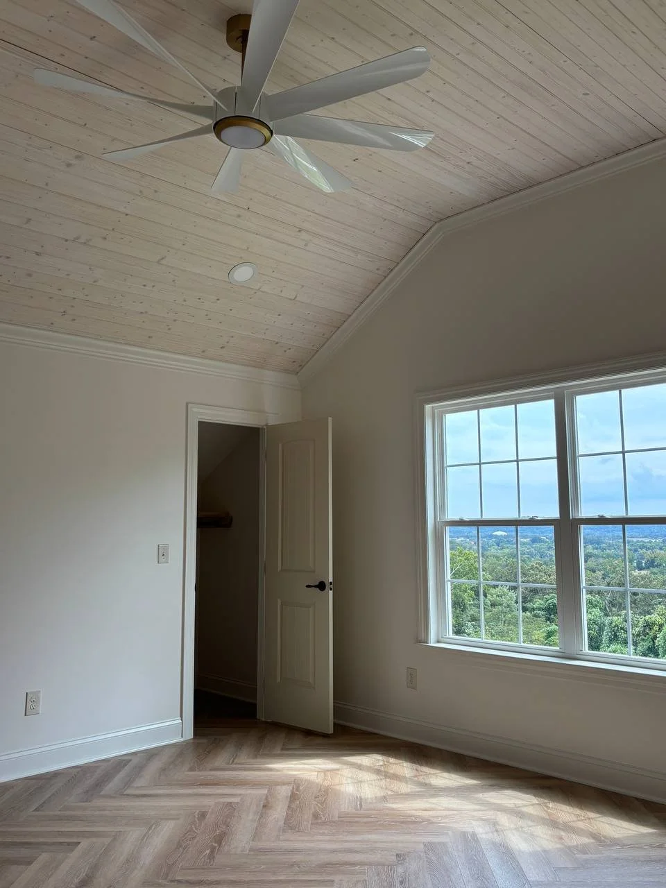 Bright master suite with scenic window views and herringbone flooring in a Chattanooga TN home addition.