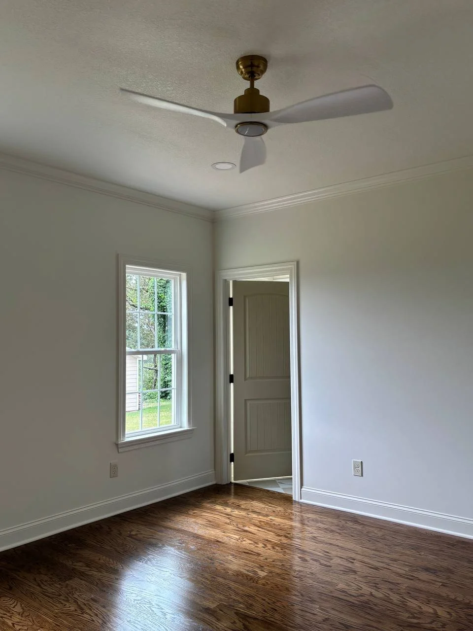 Guest bedroom in Chattanooga TN home addition with hardwood floors, large window, and modern ceiling fan.