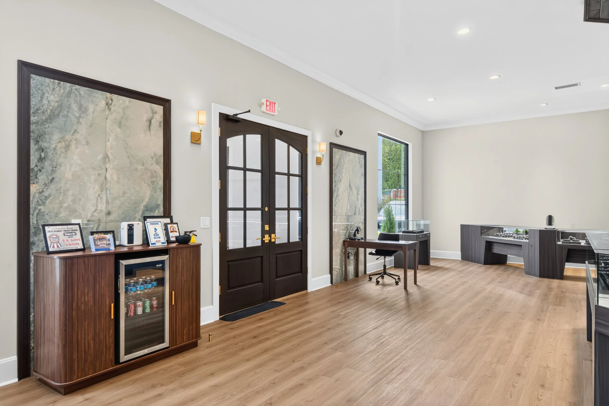 Elegant jewelry store entrance in Cleveland, TN, featuring custom wood-and-glass doors, stone accent panels, warm LVP flooring, integrated display cases, and refined wall lighting, designed and built by local commercial builder VMH Construction.