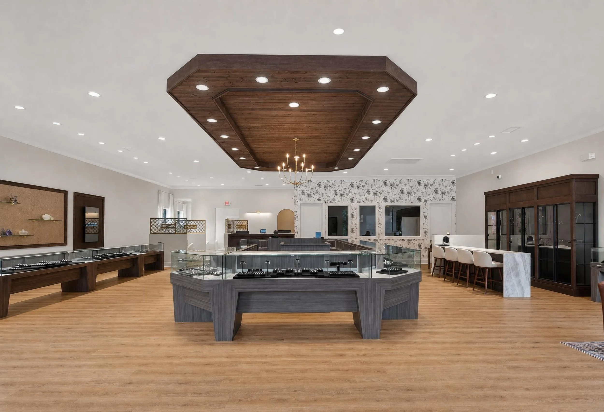 Custom jewelry showroom in Cleveland, TN, featuring glass display cases, LVP flooring, extensive recessed lighting, an elegant chandelier, and a dramatic wood-paneled ceiling feature, designed and built by local commercial builder VMH Construction.