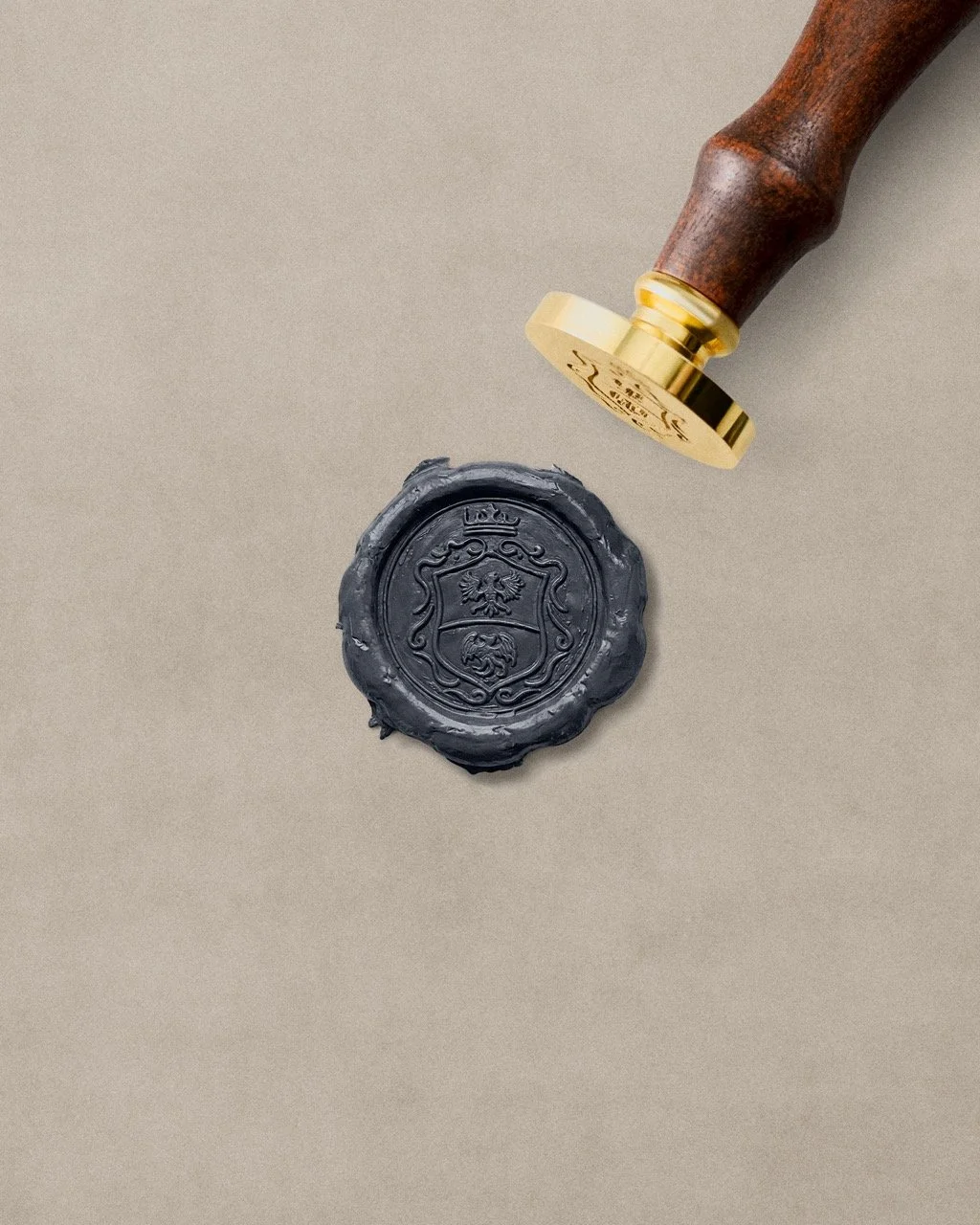 A wax seal with an emblem and a wax stamp with a handle resting on a flat surface.
