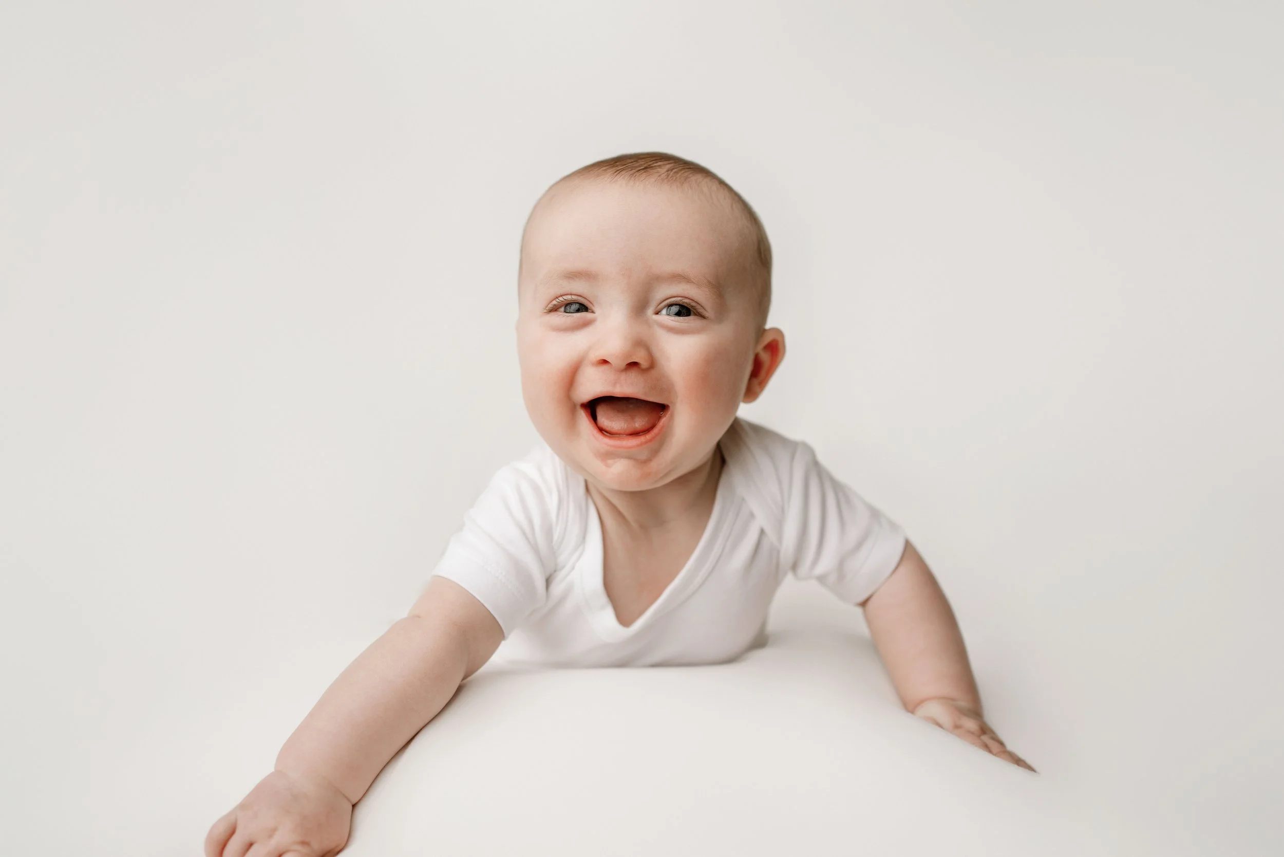 milestone session with 6 month old baby doing tummy time with genuine big smiles