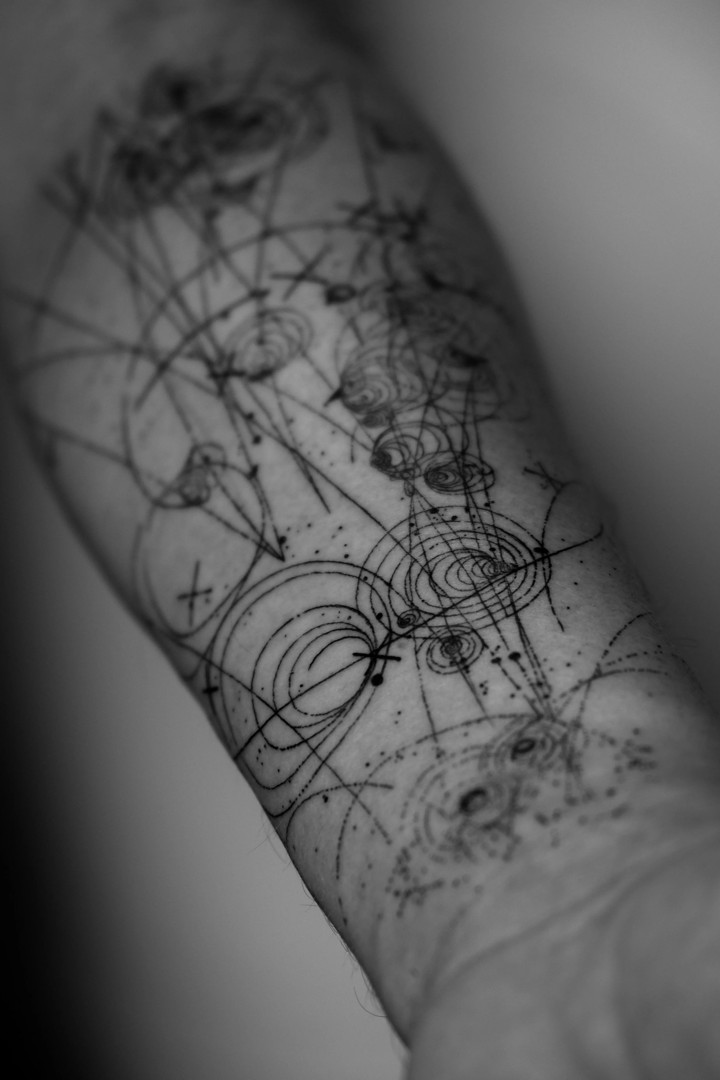 Tattoo am Arm mit geometrischen und spiralförmigen Mustern in Schwarz-Weiß.