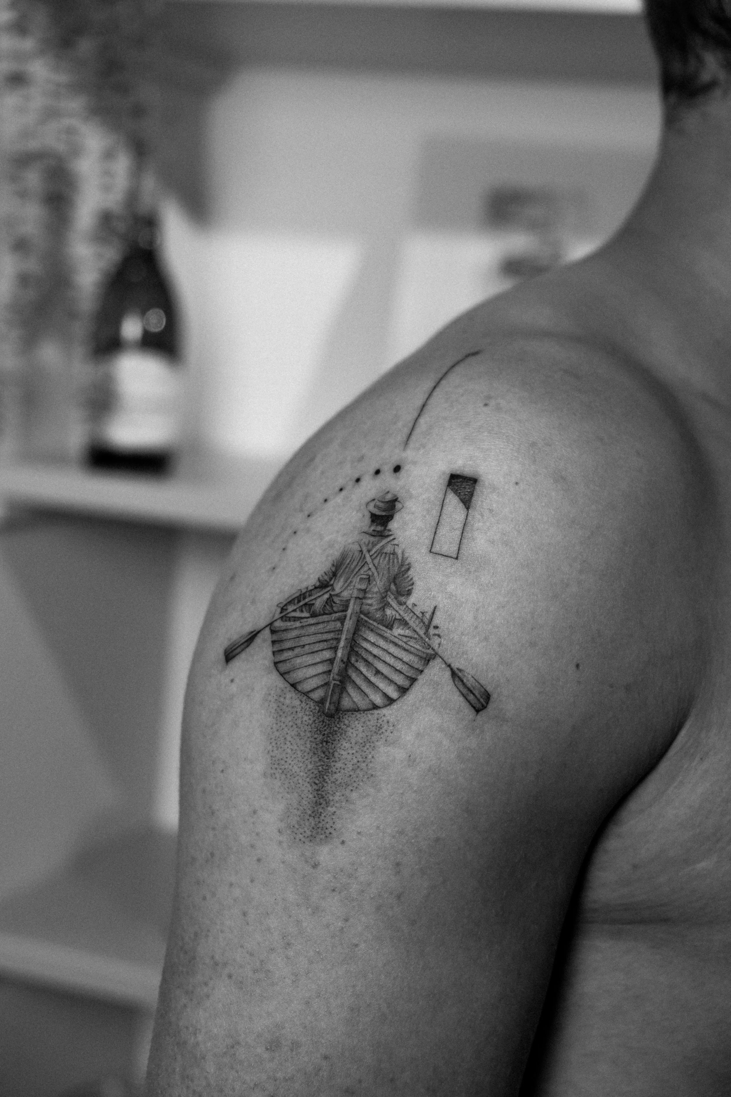 Detailliertes Schwarz-weiß-Tattoo eines Mannes im Boot auf der Schulter.