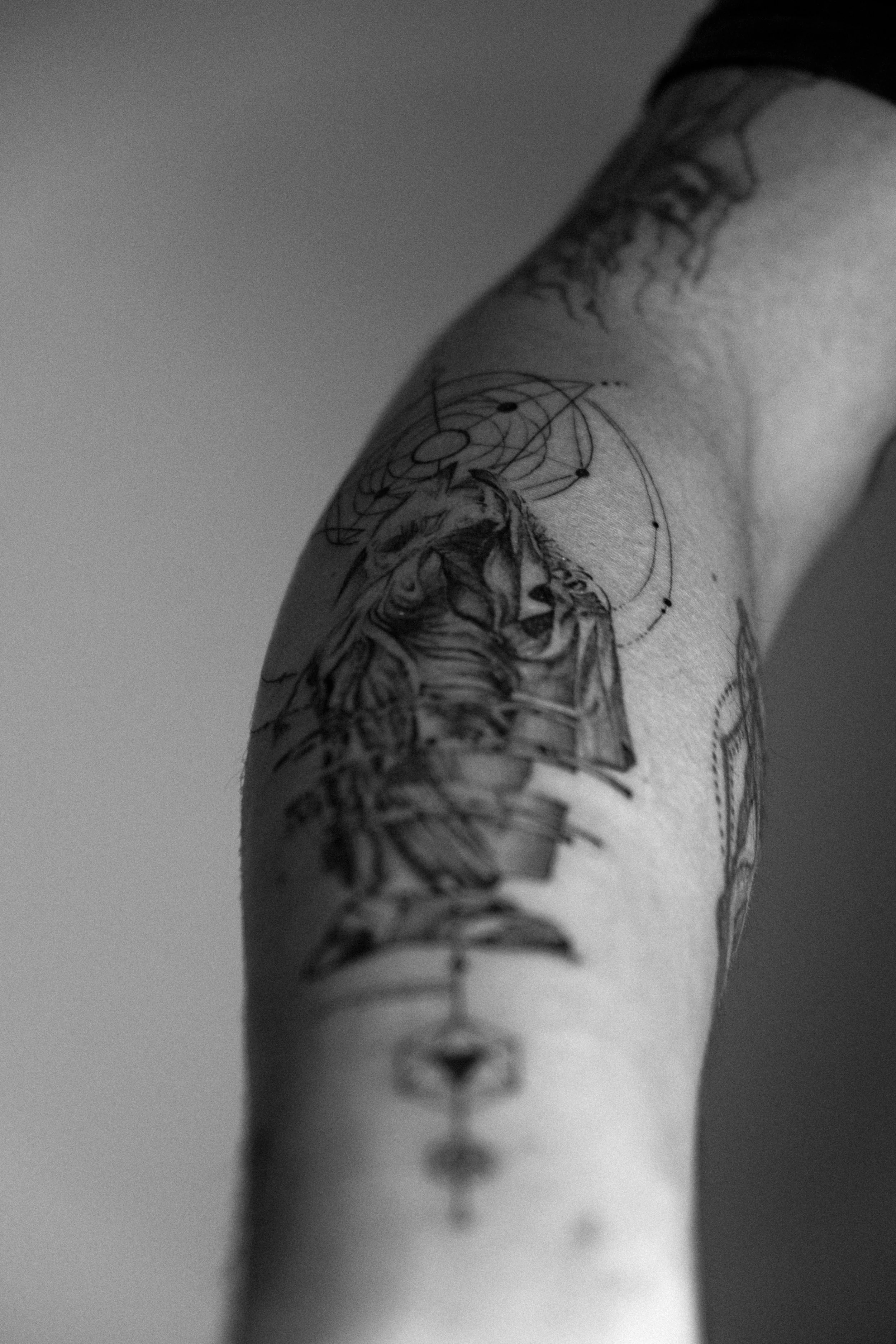 Schwarze Tätowierungen auf dem Arm, darunter ein Tiger, geometrische Muster und astronomische Symbole.