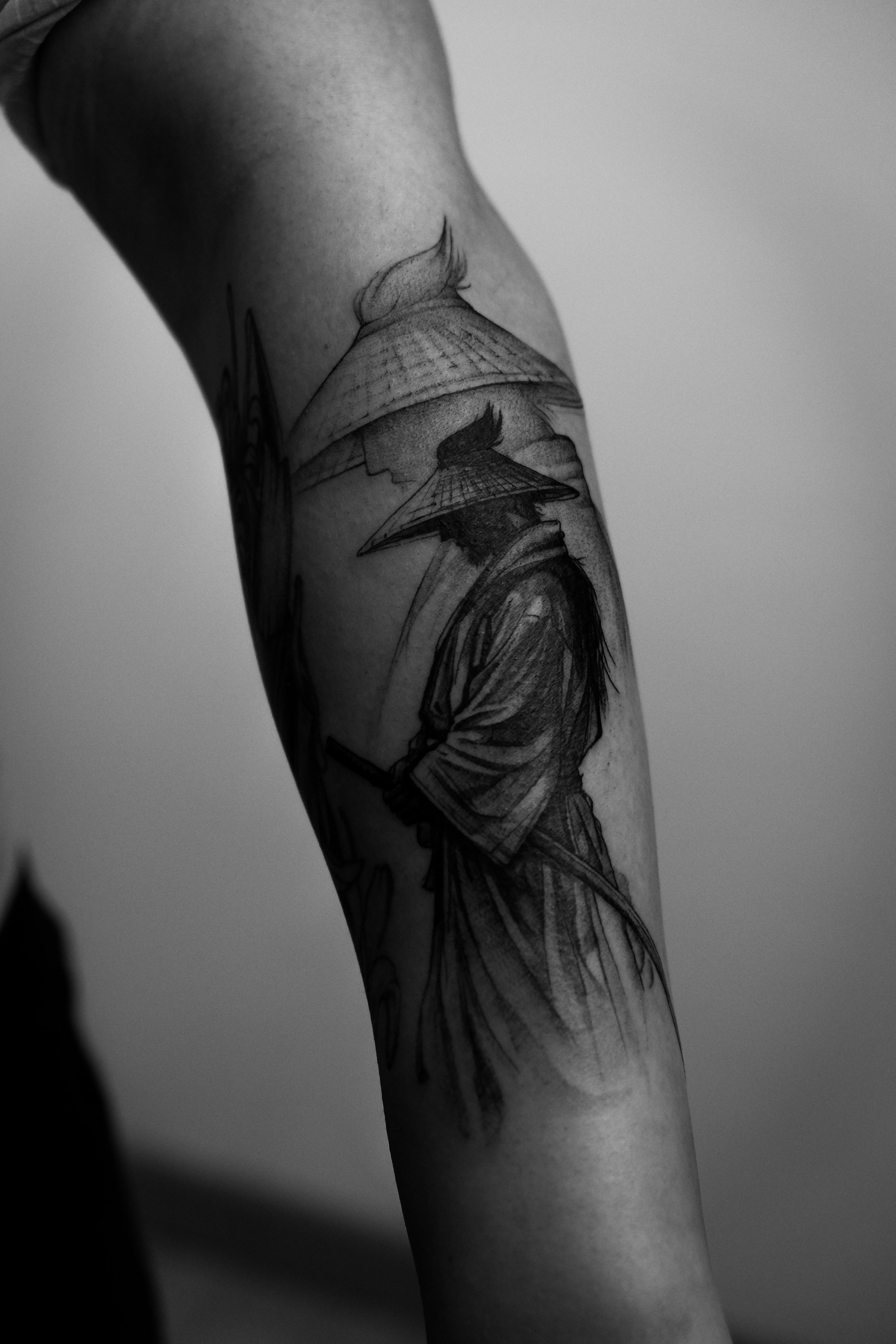 Schwarz-weiße Tätowierung eines Samurai-Kriegers mit traditioneller Kleidung und Katanas auf dem Arm.