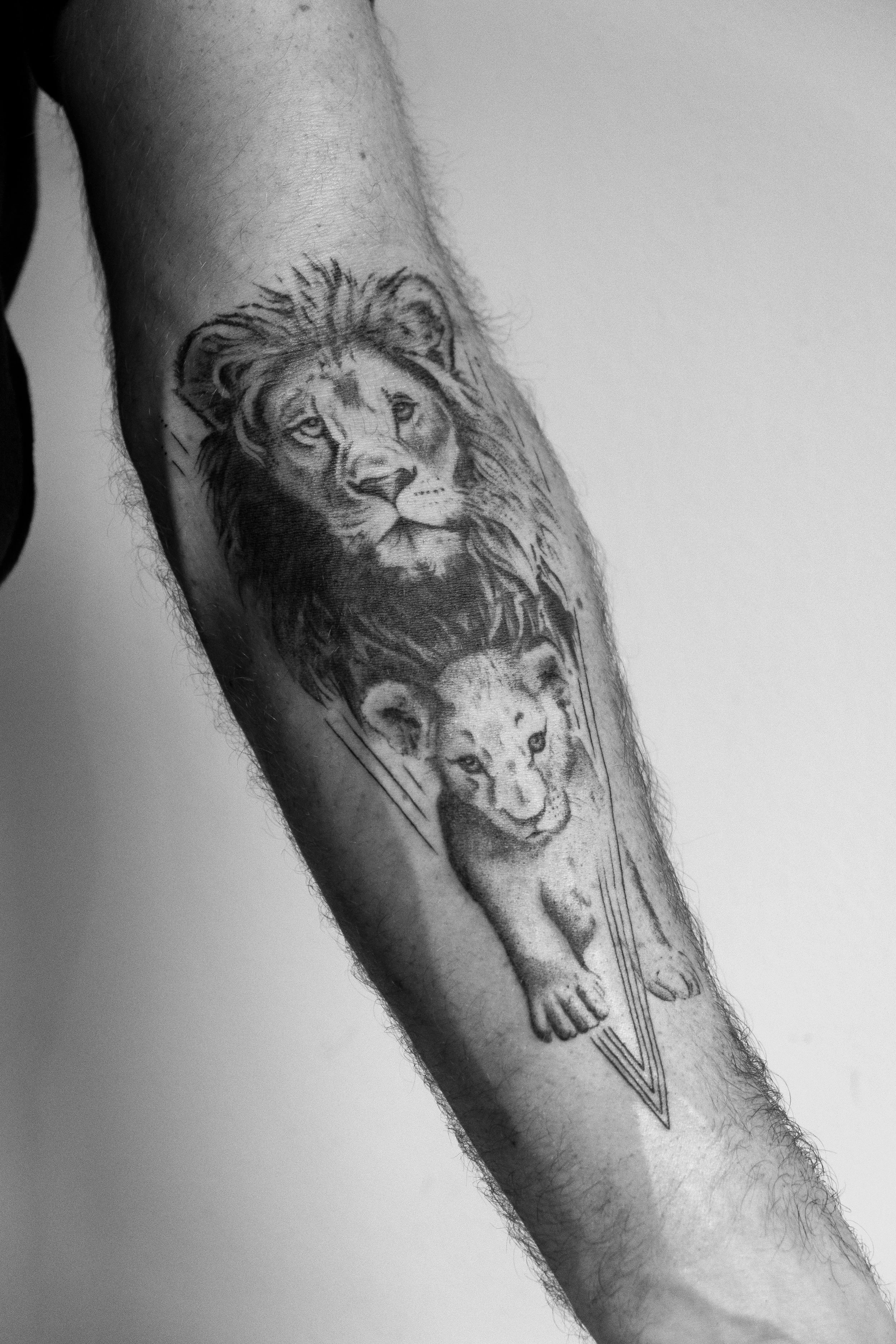 Tattoo eines Löwen und eines Löwenjungens auf einem Arm.