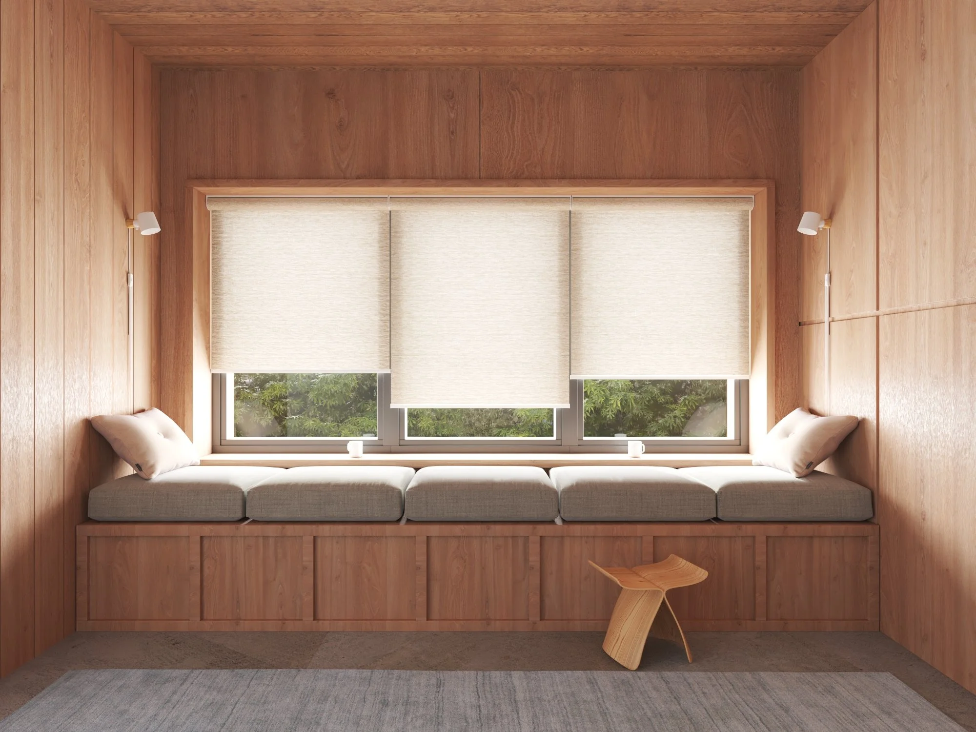 A cozy wooden room with built-in window seat with cushions, two small pillows, and a view of greenery outside. There is a small wooden stool in front of the seat and a gray carpet on the floor.