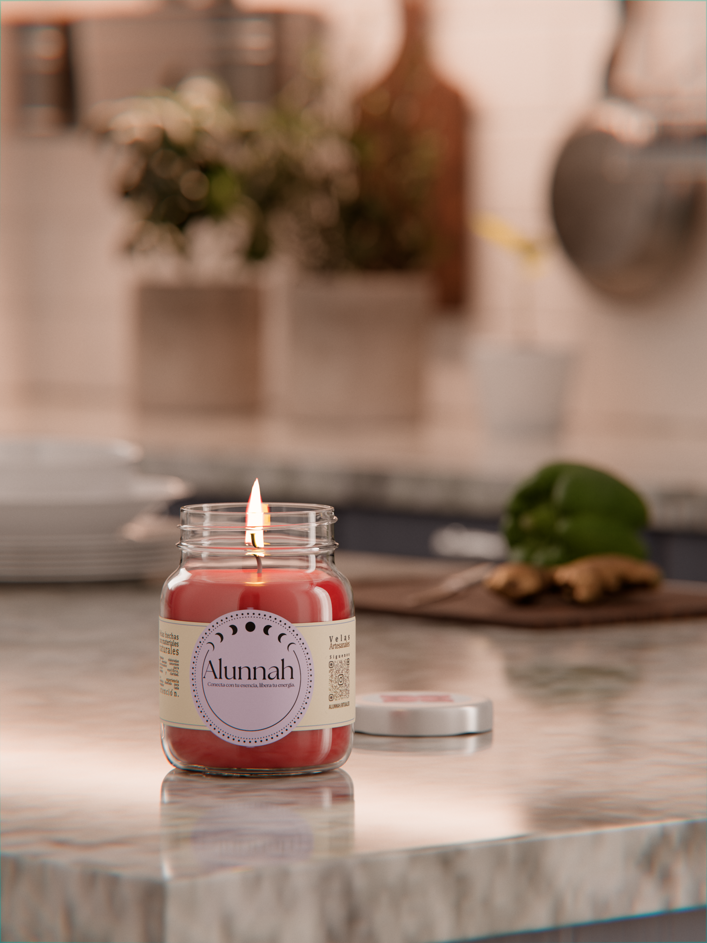 Red candle in a jar with a label reading 'Alunnah' on a marble countertop, with a lit flame. background includes blurred potted plants and kitchen items.