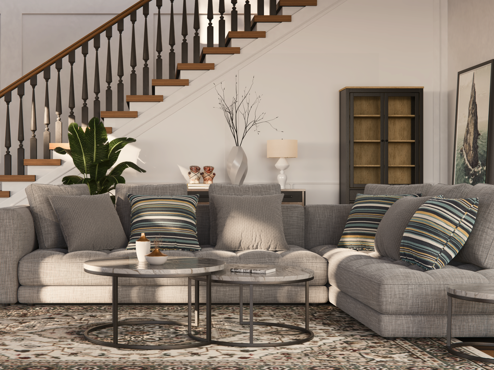 Living room with beige sectional sofa, striped and solid pillows, marble-top coffee tables, large green plant, staircase with dark railing, tall cabinet, framed art, lamp, and decorative items against white walls.