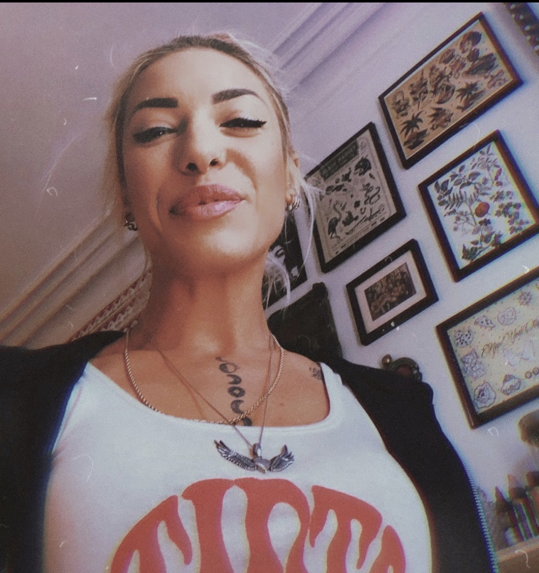woman smiling in a selfie with pictures on her wall as the background