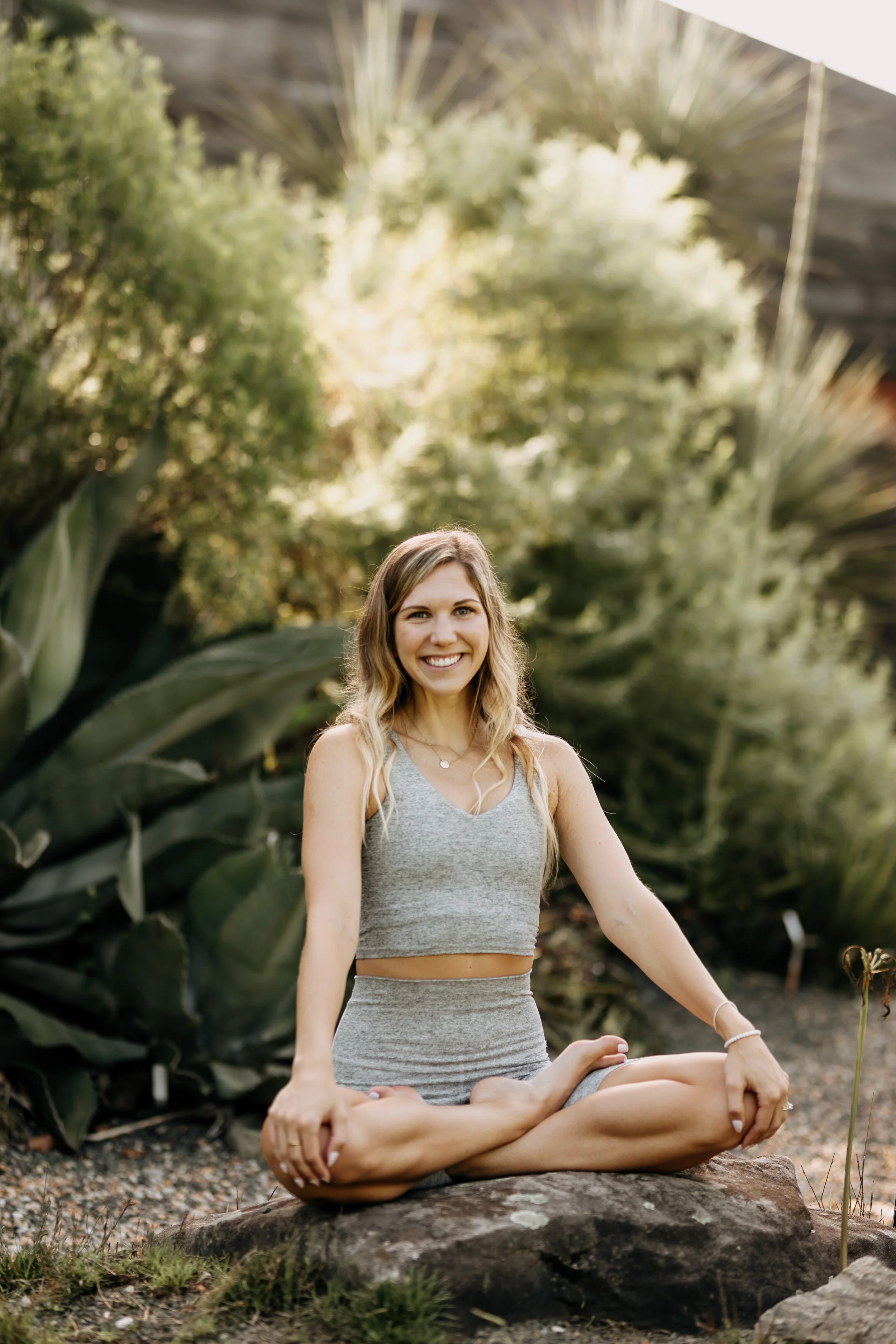 blonde woman smiling in a cross legged yoga pose