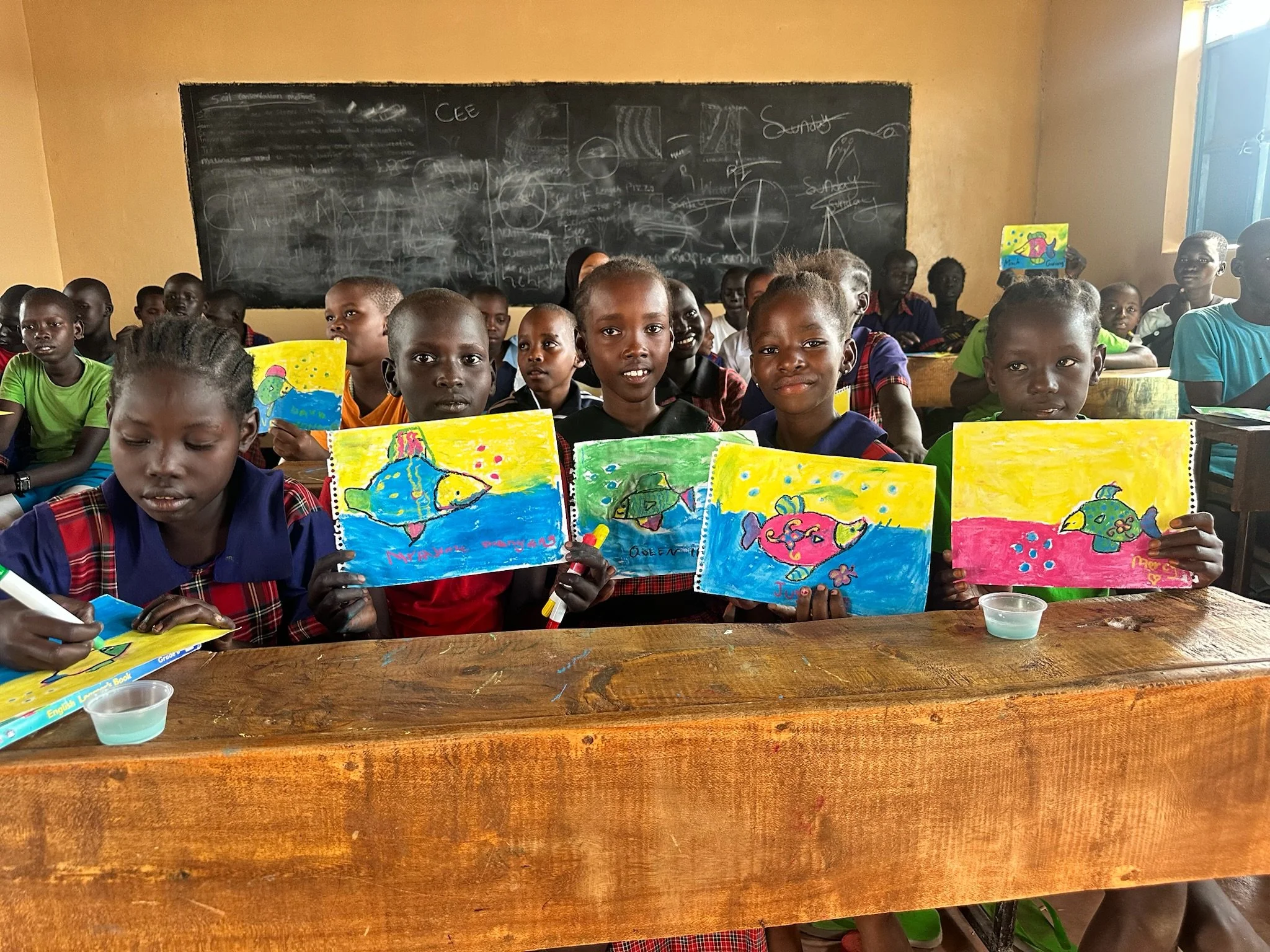 a group of kenyan school children holding up their artwork