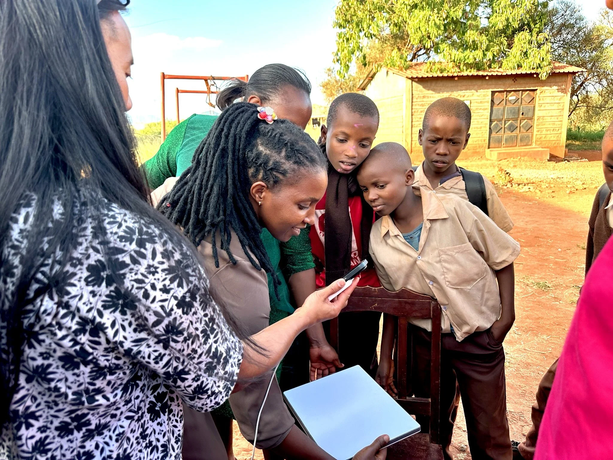 a small group of school kids crowding around a teacher as she holds a starlink device