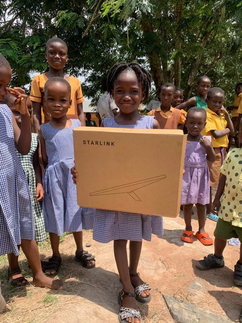 young girl in africa holding a starlink box and smiling
