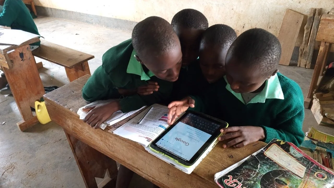 image of a small group of Kenyan school kids crowding around a tablet with google showing