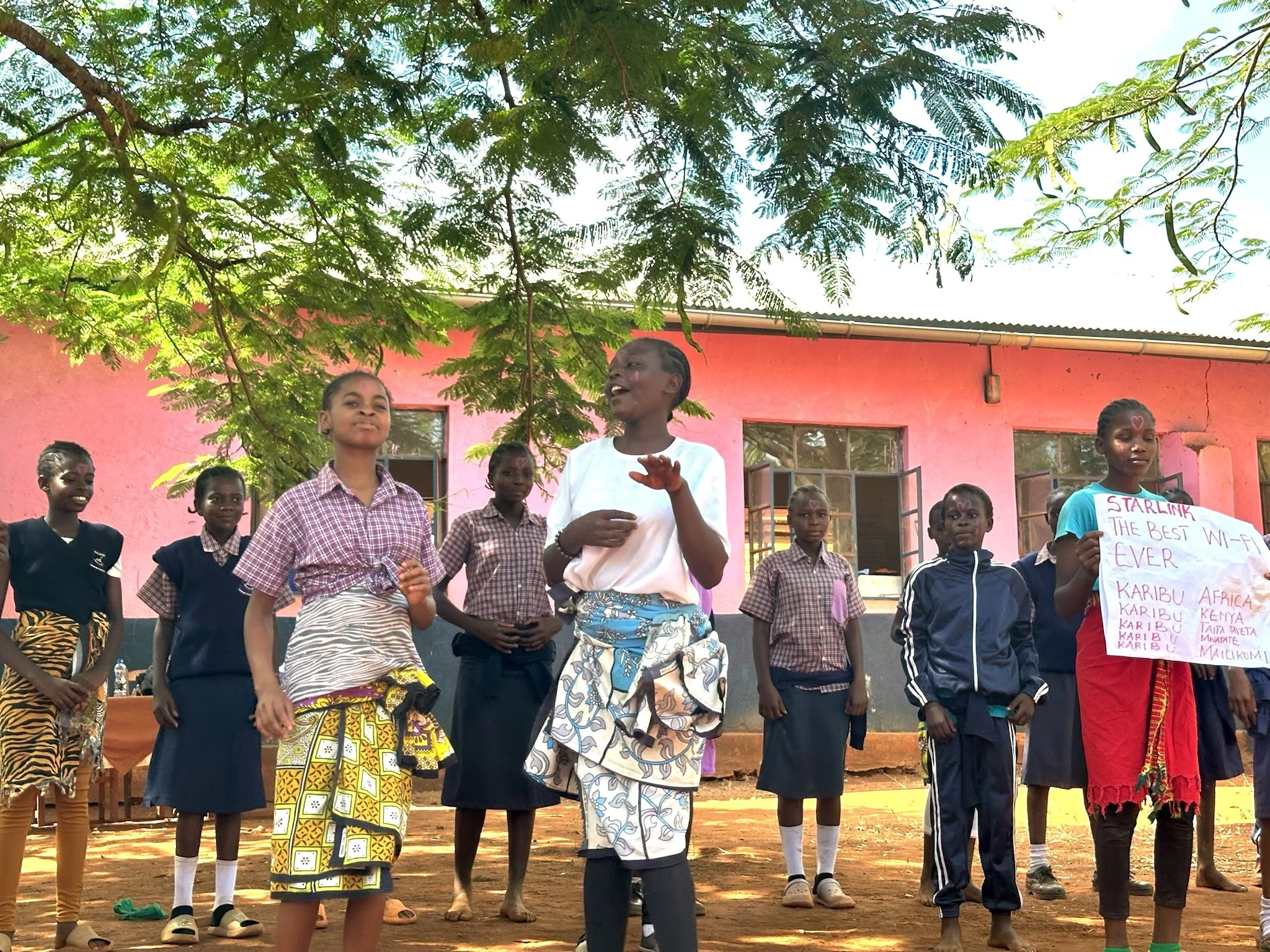a group of afrcian school girls standing outside and presenting