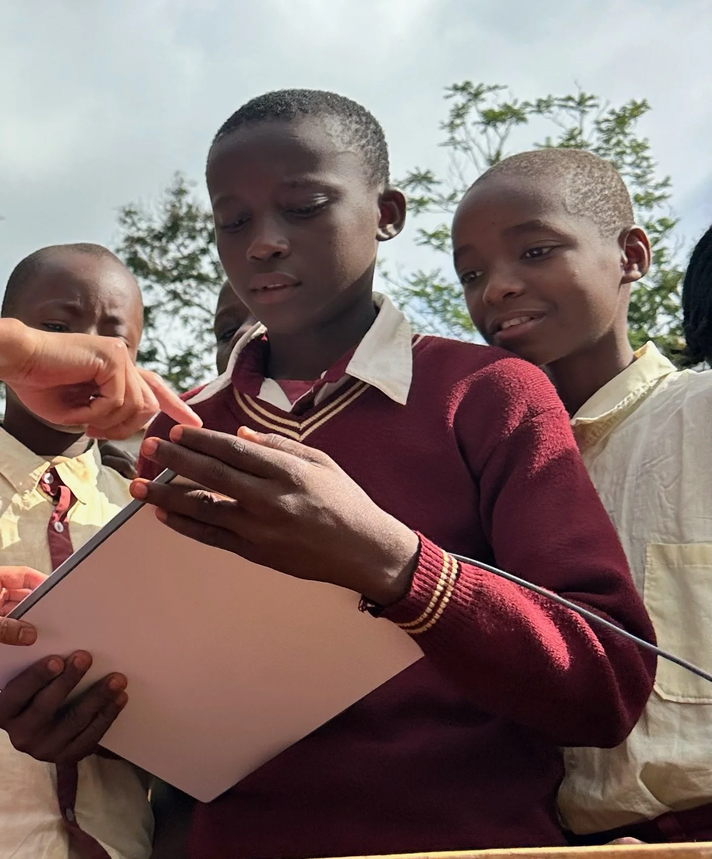 image of a young kenyan boy holding a starlink with another boy smiling behind him