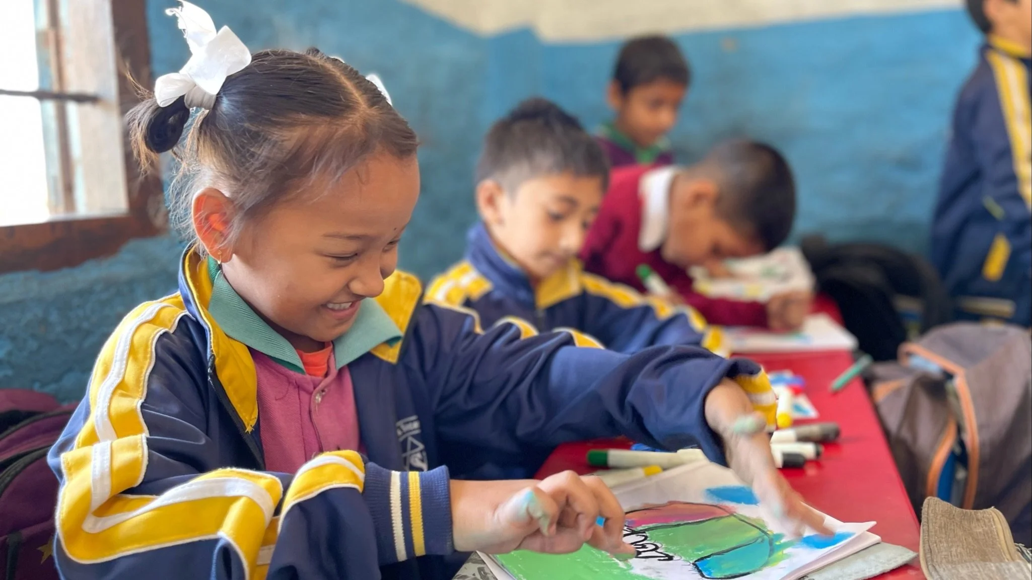 a young girl smiling while she works on her art in front of her