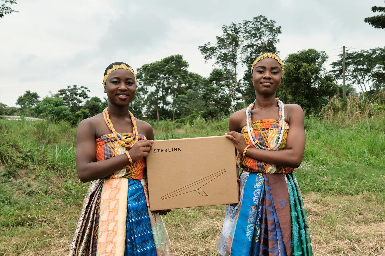 two young women holding up a starlink box in ghana